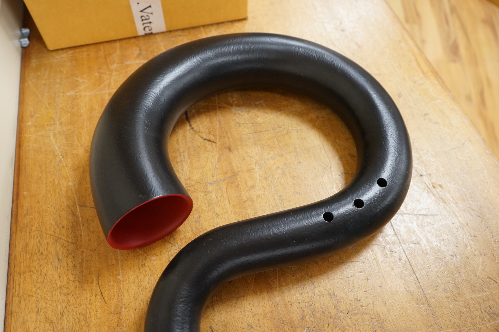 A black painted serpent open hole wind musical instrument, with brass neck (missing mouthpiece).